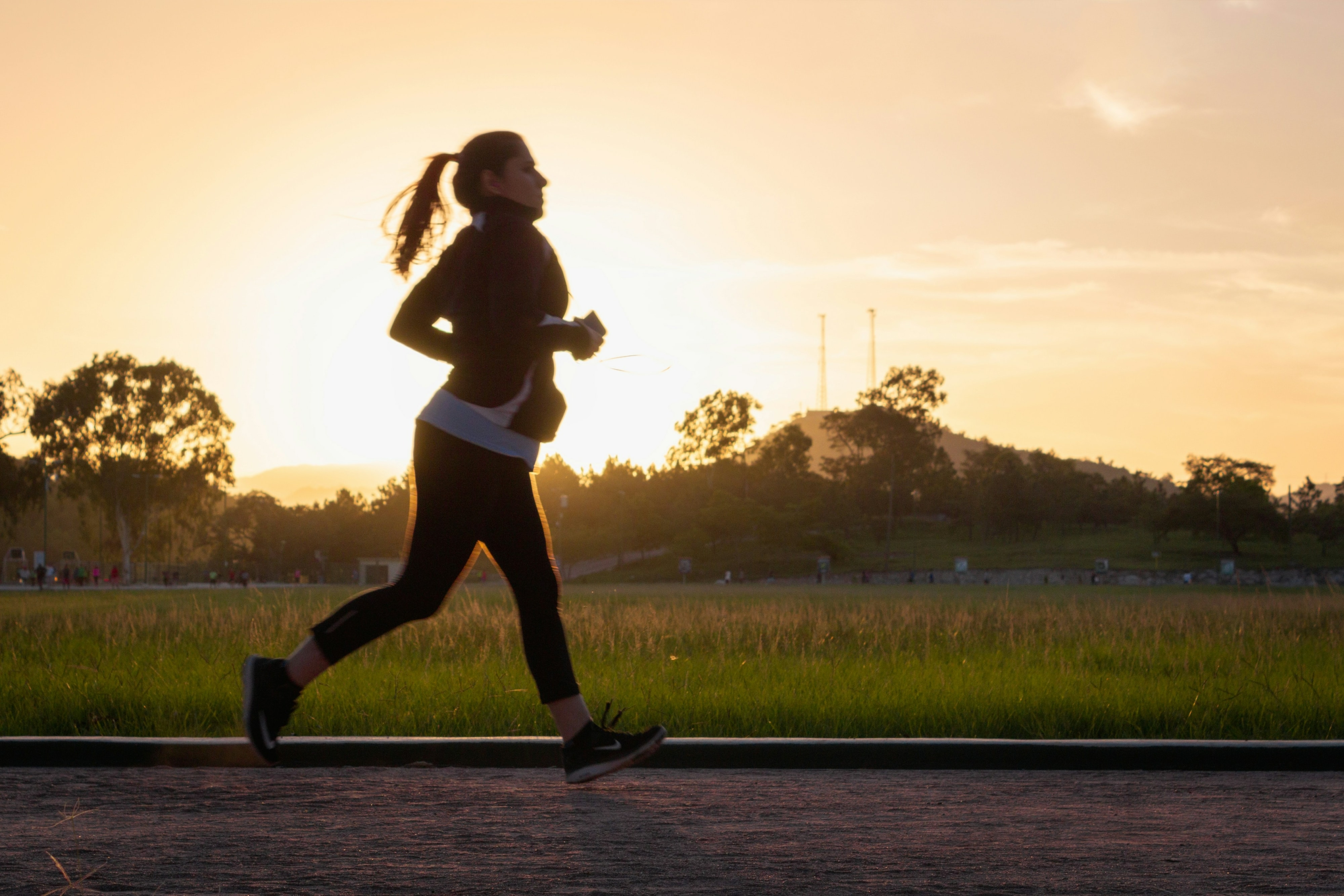 woman running outside with sun behind her
