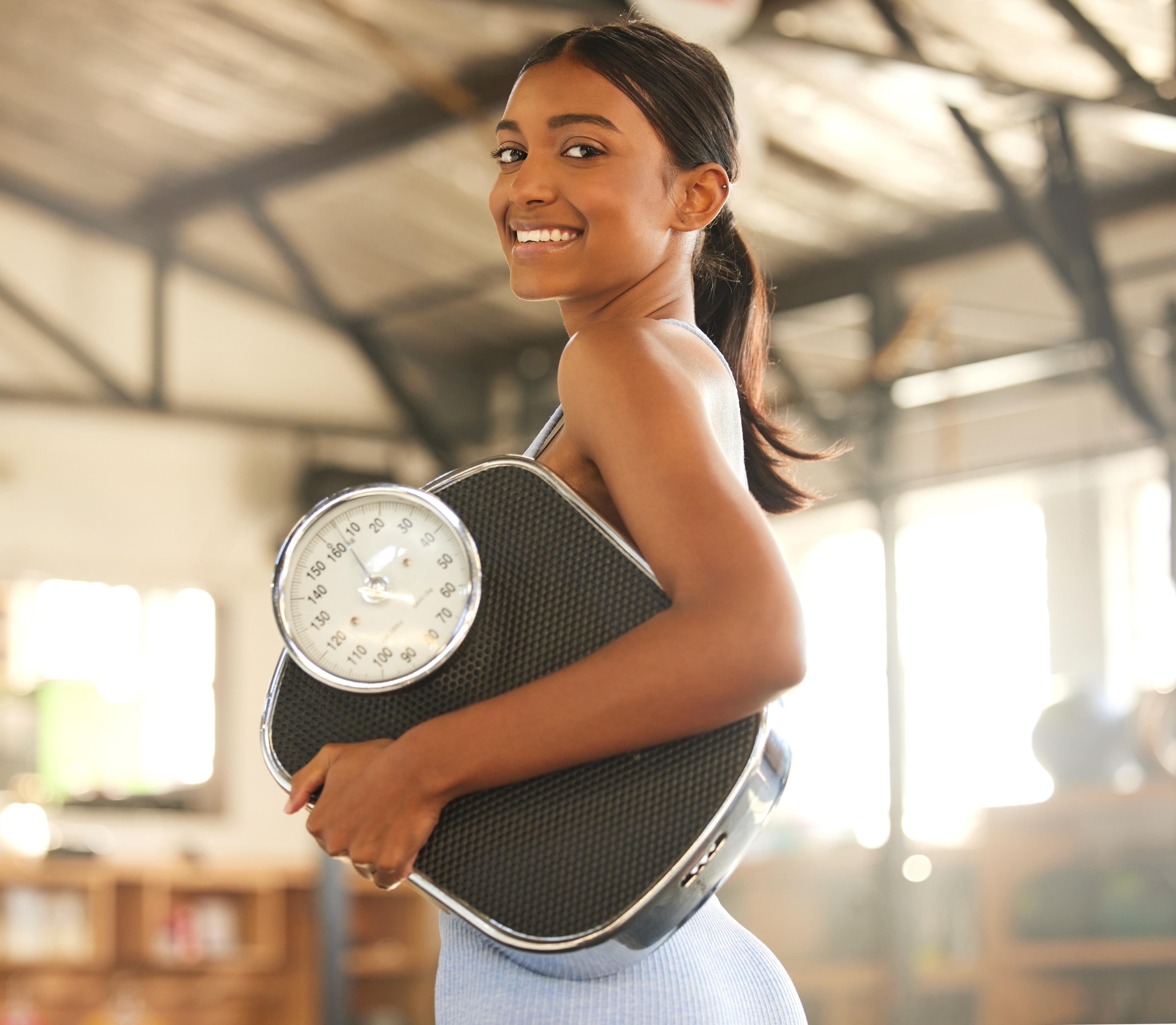 Woman holding a scale under her arm in the gym
