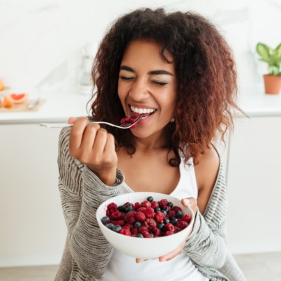 happy woman eating a bowl of berries