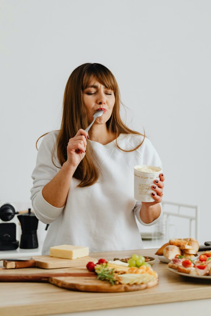 woman eating from ice cream pint in kitchen